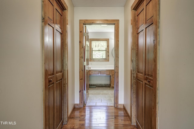 corridor featuring a textured ceiling and light hardwood / wood-style floors