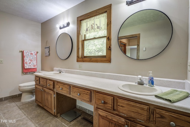 bathroom with tile patterned floors, vanity, a textured ceiling, and toilet