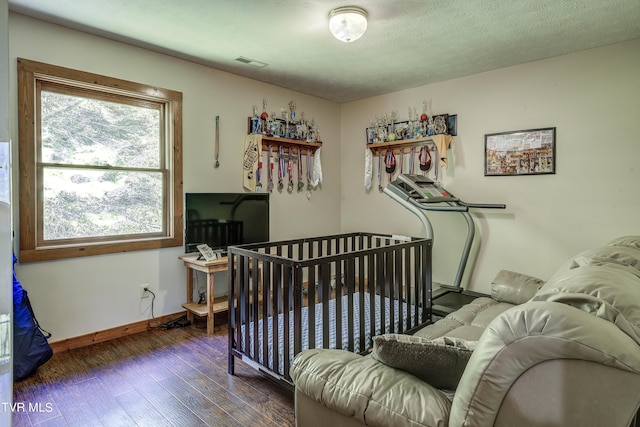 bedroom with a textured ceiling, dark wood-type flooring, and multiple windows