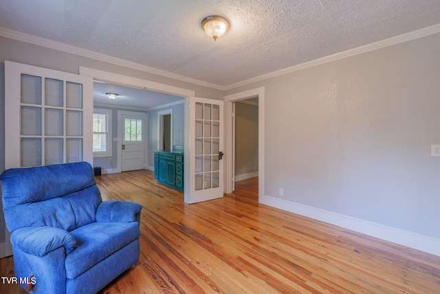 unfurnished room with a textured ceiling, light hardwood / wood-style floors, and ornamental molding