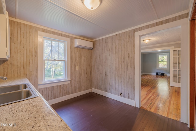 kitchen with wood walls, crown molding, a wall unit AC, dark hardwood / wood-style floors, and sink