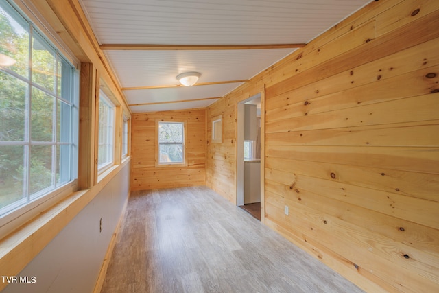 interior space with wooden walls, lofted ceiling with beams, and hardwood / wood-style flooring