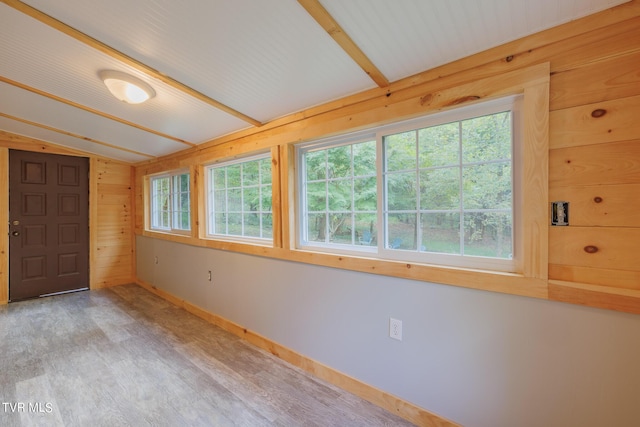 interior space with vaulted ceiling with beams and wood walls