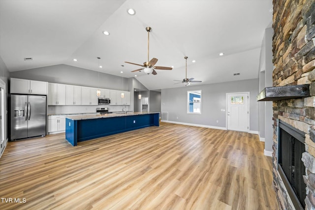 kitchen featuring white cabinets, light hardwood / wood-style flooring, blue cabinetry, appliances with stainless steel finishes, and vaulted ceiling