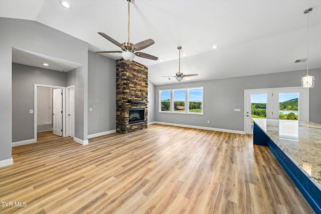 unfurnished living room with lofted ceiling, a fireplace, ceiling fan, and light hardwood / wood-style flooring