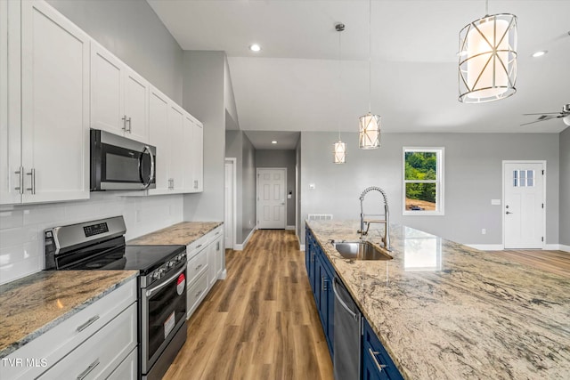 kitchen featuring appliances with stainless steel finishes, blue cabinets, white cabinetry, and pendant lighting