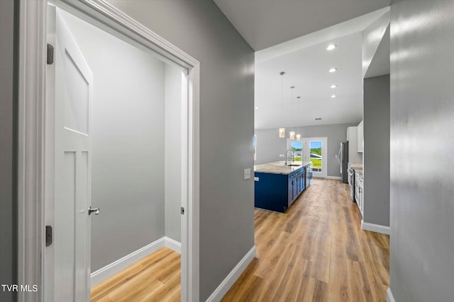 corridor with light wood-type flooring and sink