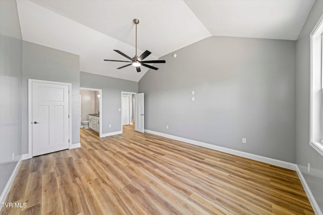 unfurnished bedroom with light hardwood / wood-style floors, multiple windows, vaulted ceiling, ensuite bath, and ceiling fan