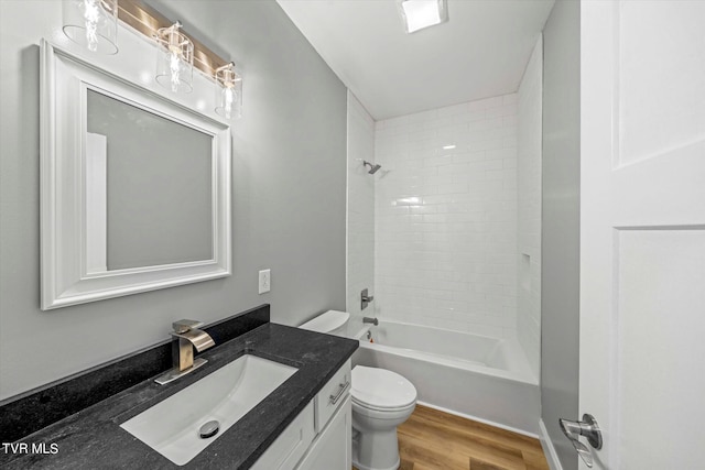 full bathroom featuring wood-type flooring, tiled shower / bath, vanity, and toilet