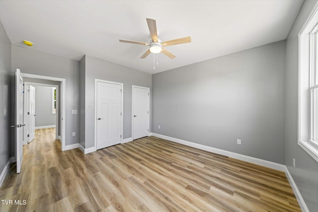 2137 Rainwater Rd, Dandridge, TN 37725 - unfurnished bedroom featuring light wood finished floors, baseboards, two closets, and a ceiling fan