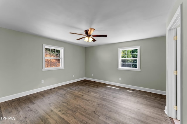 empty room with ceiling fan, plenty of natural light, and dark wood-type flooring