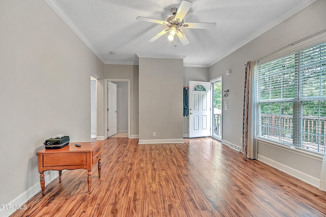 foyer entrance featuring ceiling fan, ornamental molding, a textured ceiling, and light wood-type flooring