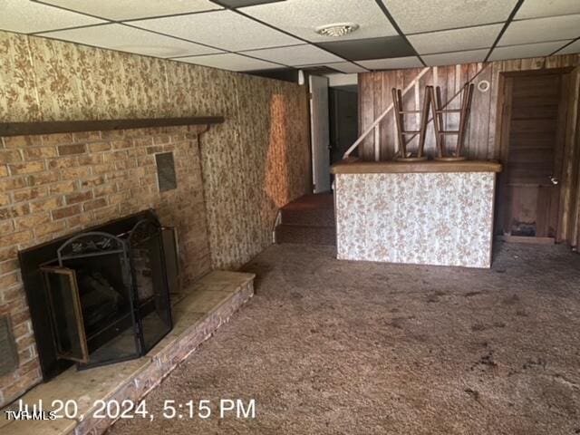 unfurnished living room with a drop ceiling and dark colored carpet