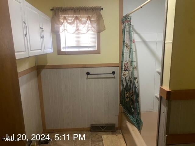 bathroom with shower / bath combo with shower curtain and tile patterned floors