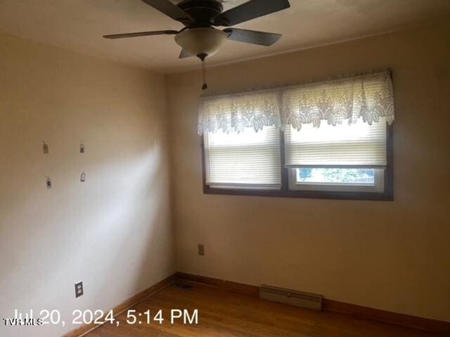 spare room featuring a baseboard heating unit, wood-type flooring, and ceiling fan