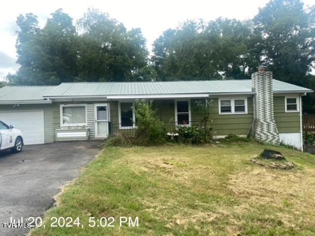 single story home with a porch, a garage, and a front lawn