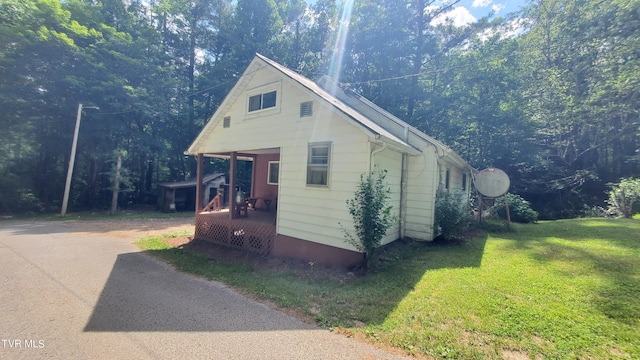 view of side of property with a yard and covered porch