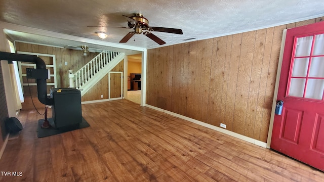 foyer with crown molding, ceiling fan, wood-type flooring, a textured ceiling, and wood walls