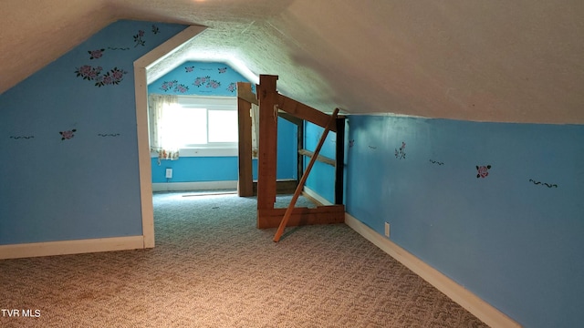 additional living space featuring lofted ceiling, carpet floors, and a textured ceiling