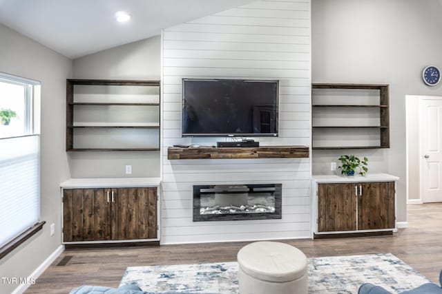 living room with hardwood / wood-style flooring, lofted ceiling, and a fireplace