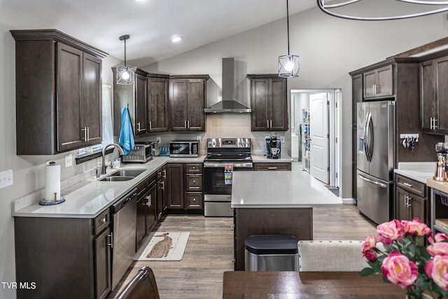 kitchen featuring pendant lighting, wall chimney range hood, sink, and appliances with stainless steel finishes