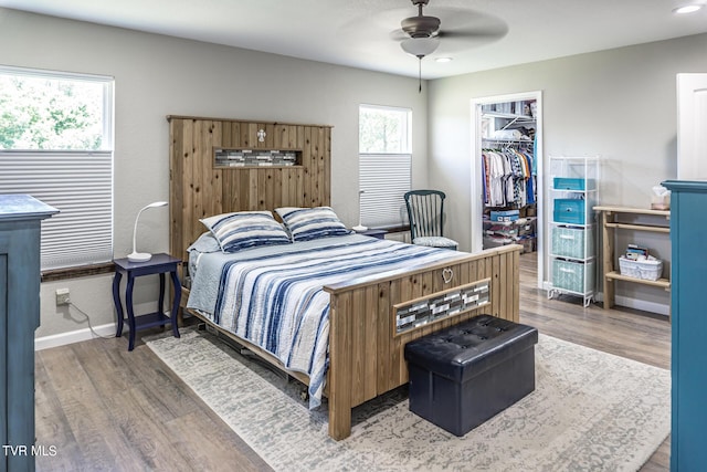 bedroom featuring hardwood / wood-style flooring, ceiling fan, a spacious closet, and a closet