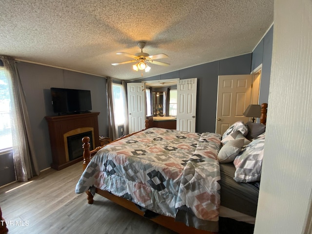 bedroom featuring ceiling fan, light wood-type flooring, and a textured ceiling