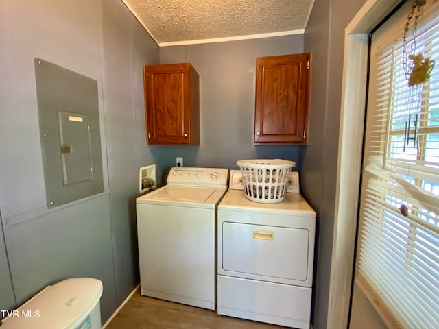 laundry area with cabinets, light hardwood / wood-style floors, independent washer and dryer, electric panel, and a textured ceiling