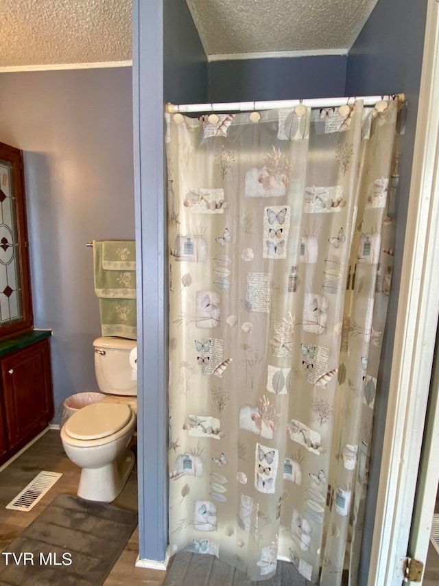 bathroom with wood-type flooring, toilet, and a textured ceiling