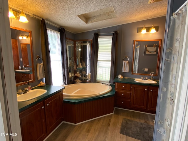 bathroom featuring a textured ceiling, a bathing tub, double sink vanity, and hardwood / wood-style flooring