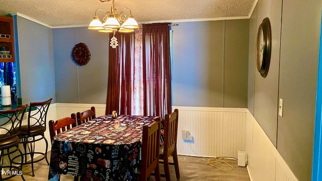 dining area featuring hardwood / wood-style floors, an inviting chandelier, ornamental molding, and a textured ceiling