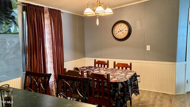 dining area with a textured ceiling, light hardwood / wood-style flooring, a chandelier, and ornamental molding