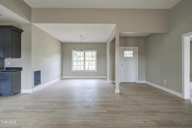 unfurnished dining area featuring light wood-type flooring and a notable chandelier