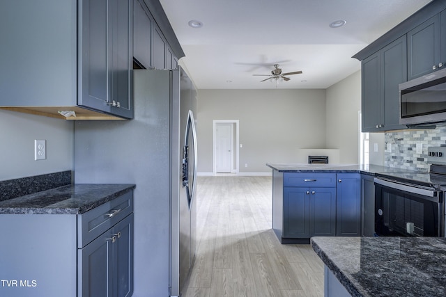 kitchen with kitchen peninsula, dark stone counters, stainless steel appliances, ceiling fan, and light hardwood / wood-style flooring