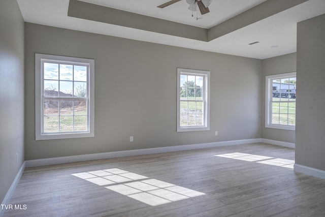 spare room featuring a tray ceiling, ceiling fan, and light hardwood / wood-style floors