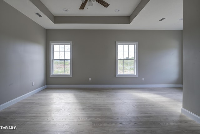 empty room featuring hardwood / wood-style floors, a raised ceiling, and ceiling fan