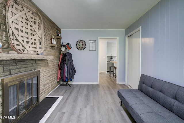 living room featuring crown molding, a fireplace, wooden walls, and light wood-type flooring