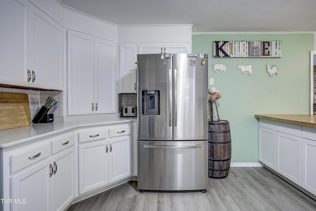 kitchen with crown molding, stainless steel fridge with ice dispenser, decorative backsplash, light wood-type flooring, and white cabinetry