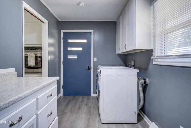 clothes washing area featuring cabinets, light wood-type flooring, washer / clothes dryer, and crown molding