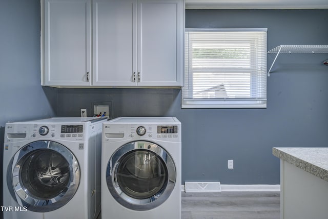 laundry room featuring cabinets, independent washer and dryer, and light hardwood / wood-style floors