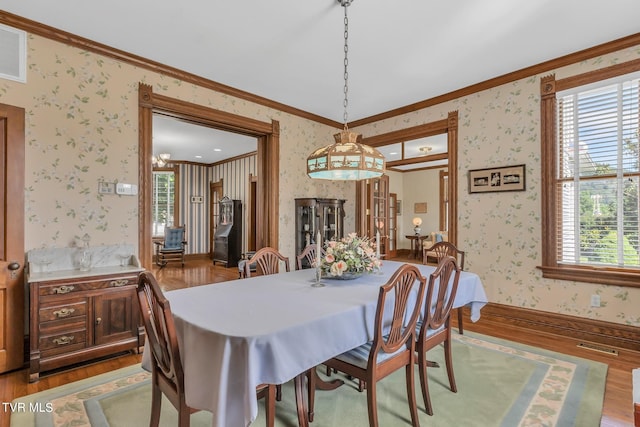 dining area featuring a notable chandelier, crown molding, and hardwood / wood-style flooring