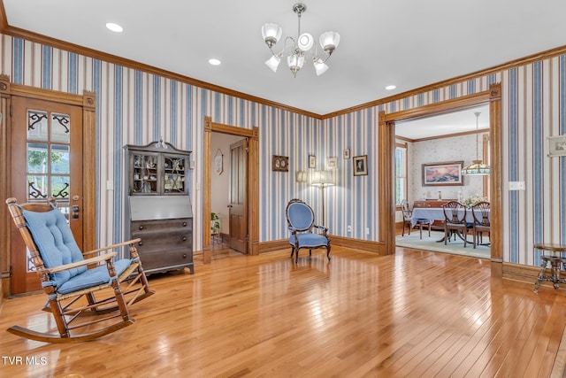 living area with ornamental molding, light hardwood / wood-style flooring, and an inviting chandelier