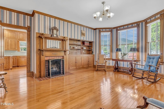 living room with a notable chandelier, ornamental molding, light wood-type flooring, and a fireplace