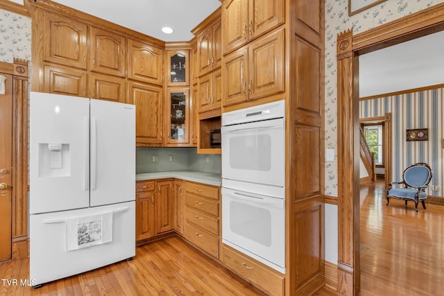 kitchen with ornamental molding, white appliances, and light wood-type flooring