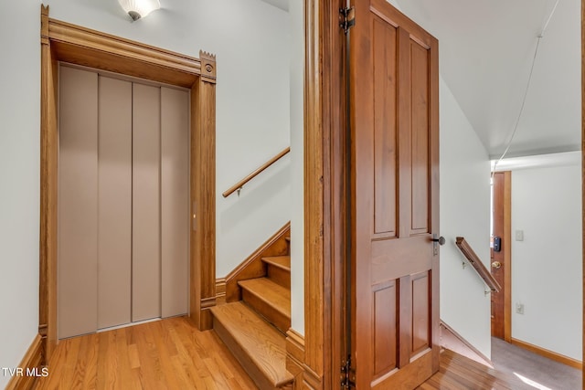 stairs featuring elevator and light wood-type flooring