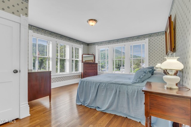 308 E Pearl Ave, Big Stone Gap, VA 24219 - bedroom with wallpapered walls, wood finished floors, and multiple windows