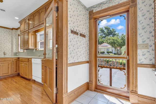 kitchen with sink, ornamental molding, light tile flooring, and white dishwasher