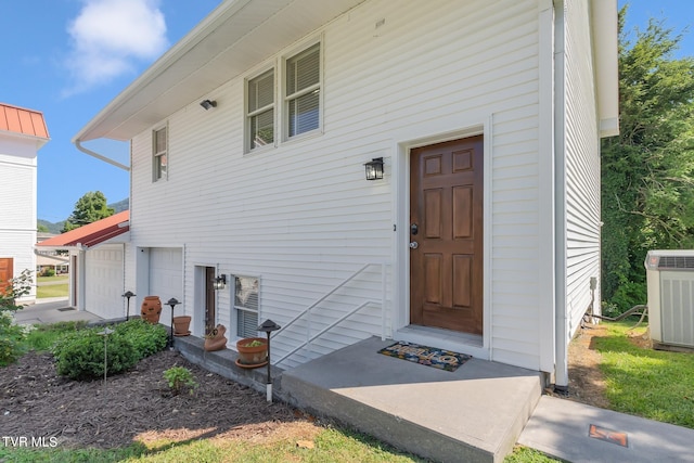 view of exterior entry with central AC and a garage