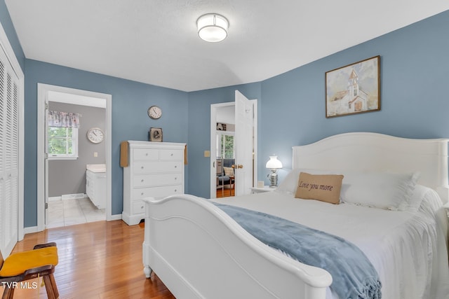 bedroom with light hardwood / wood-style floors, a closet, and connected bathroom