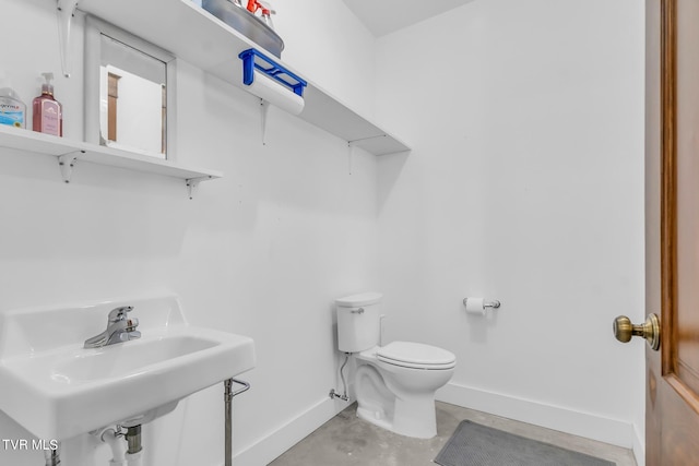 bathroom featuring sink, toilet, and concrete flooring